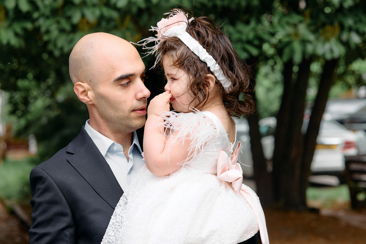 Dad holding his little gir at the garden of a church, after she's been christened.