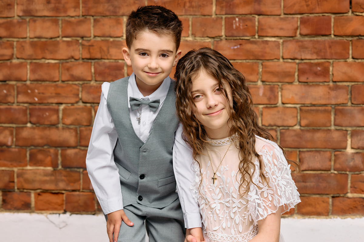 A little boy and a girl, dressed up, posing outside a church for a photo.