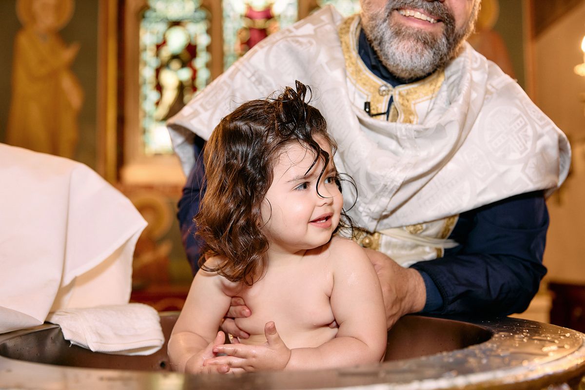 Little girl being christened. She looks very happy.