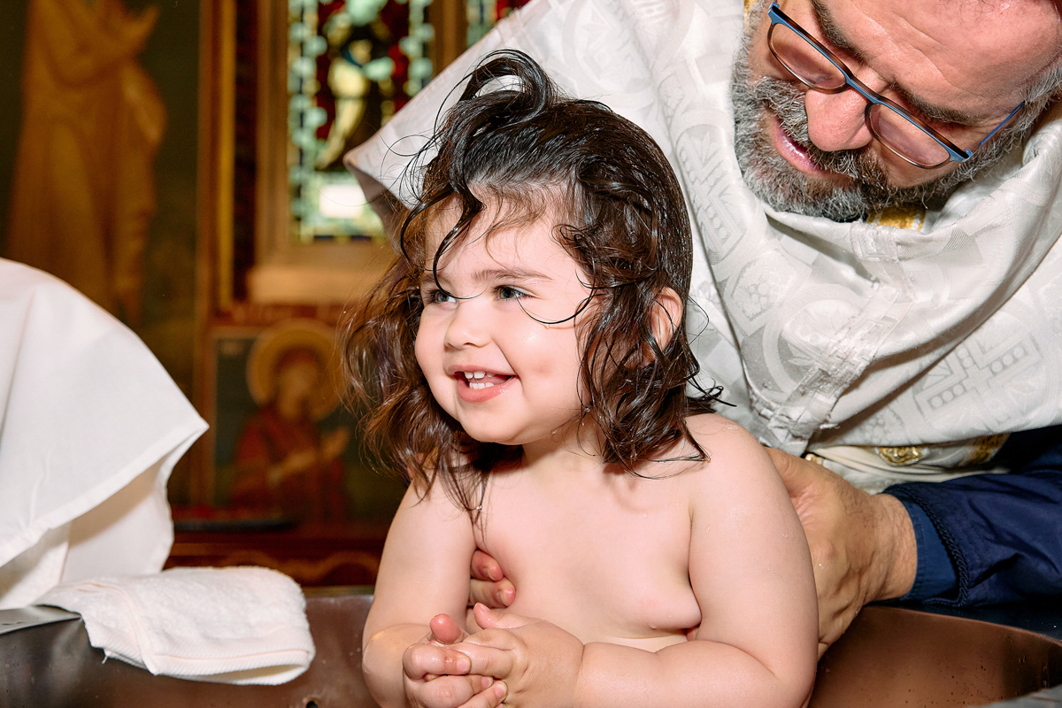 Little girl being christened. She looks very happy.
