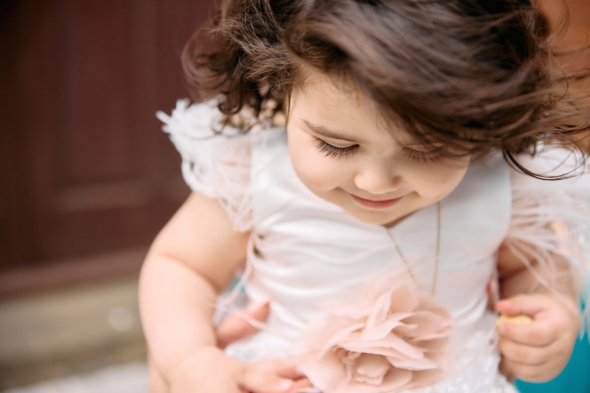 Little girl ini her christening dress looking down. You can se her beautiful big eye lashes.