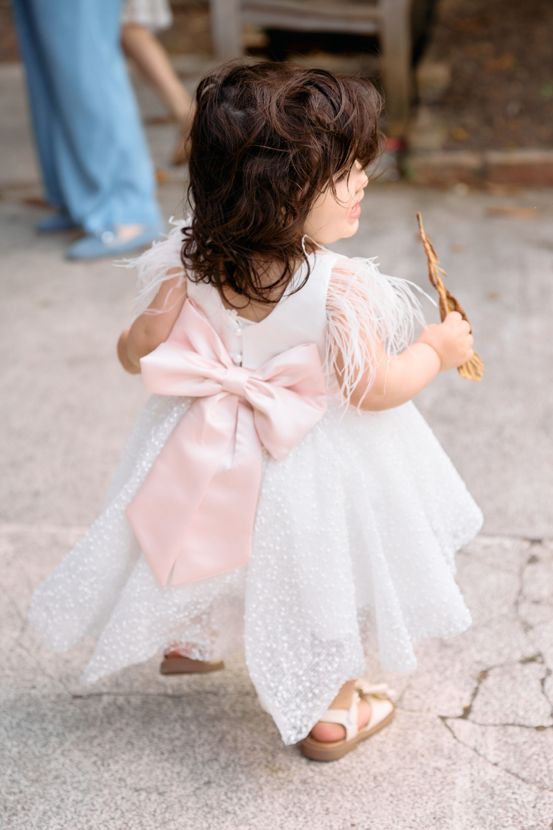 Little girll in her new christening dress after her christening outside the church showing of the bow at the back of her dress.