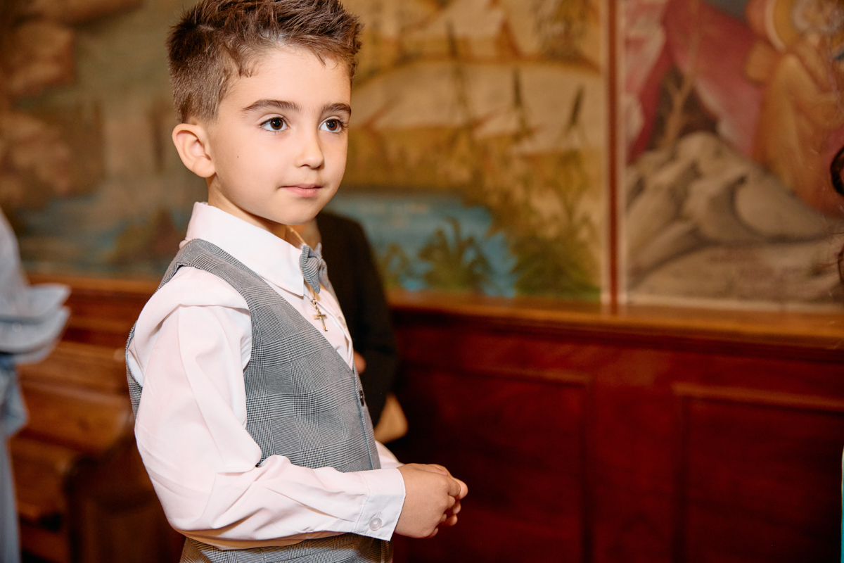 A little boy dressed up watching a christening.