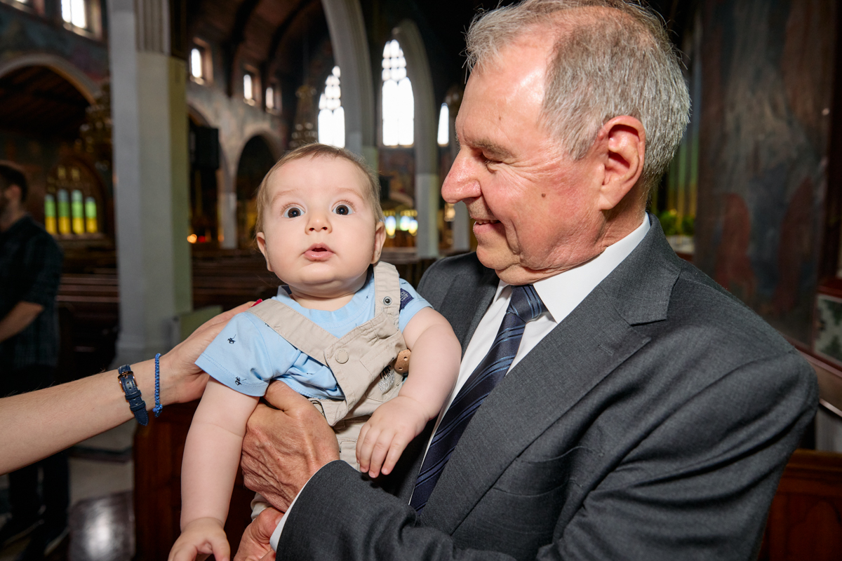 Older man holding the baby inside the church.