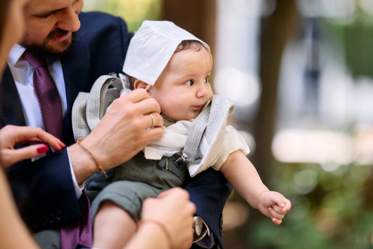 Father holding the baby, who now wears the christening cap.