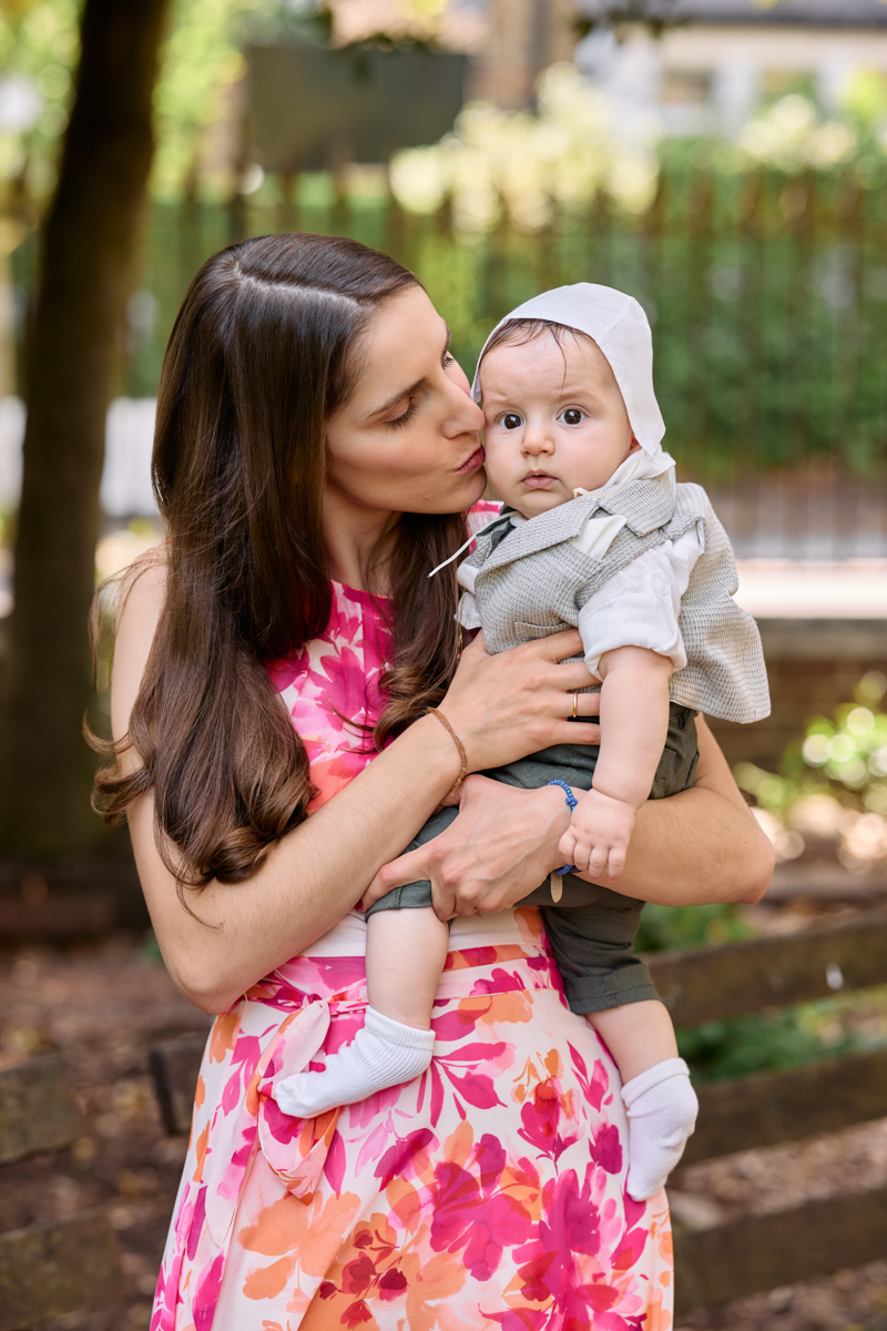 Mother holding the baby outdoors in sunlight.