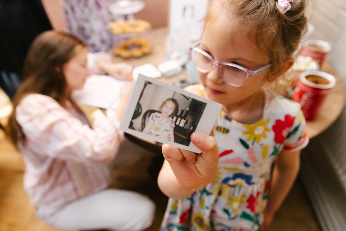 Young girl holding up a photo .