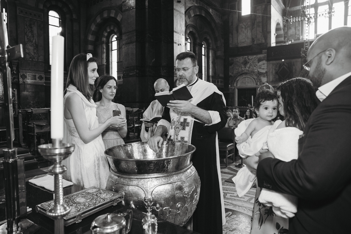a priest reading during a baptism ceremony in a greek orthodox church in London