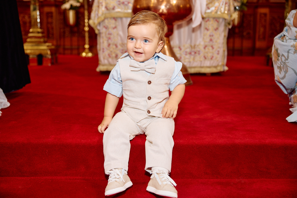 Little boy after his christening sitting down in a church.
