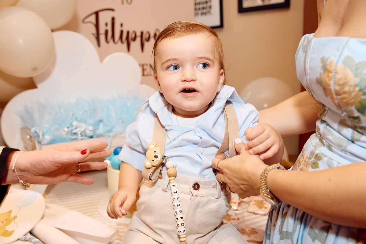 Little boy in his new christening clothes sitting on a table.