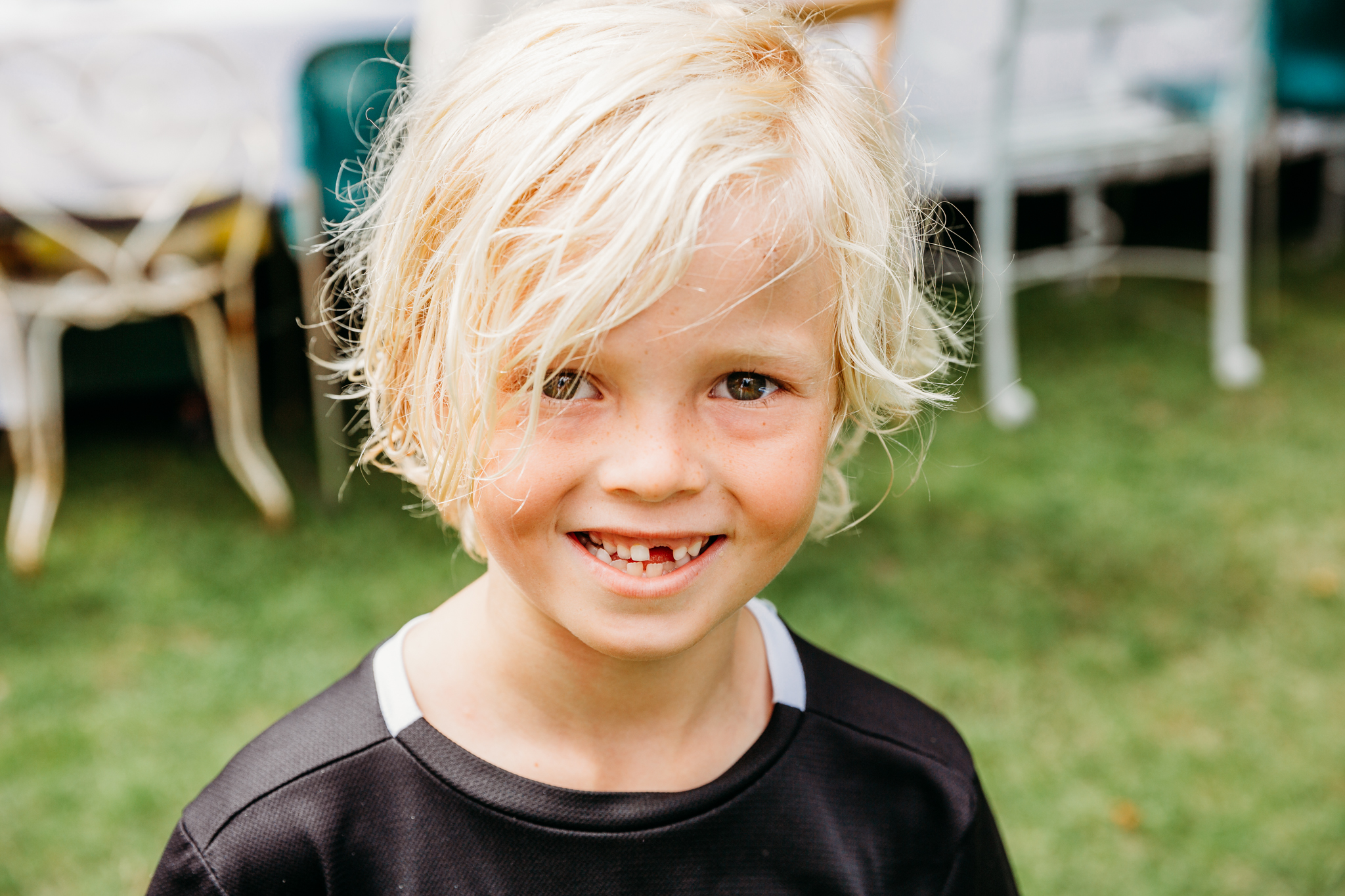 Little boy with a missing tooth looking at the camera and smiling.