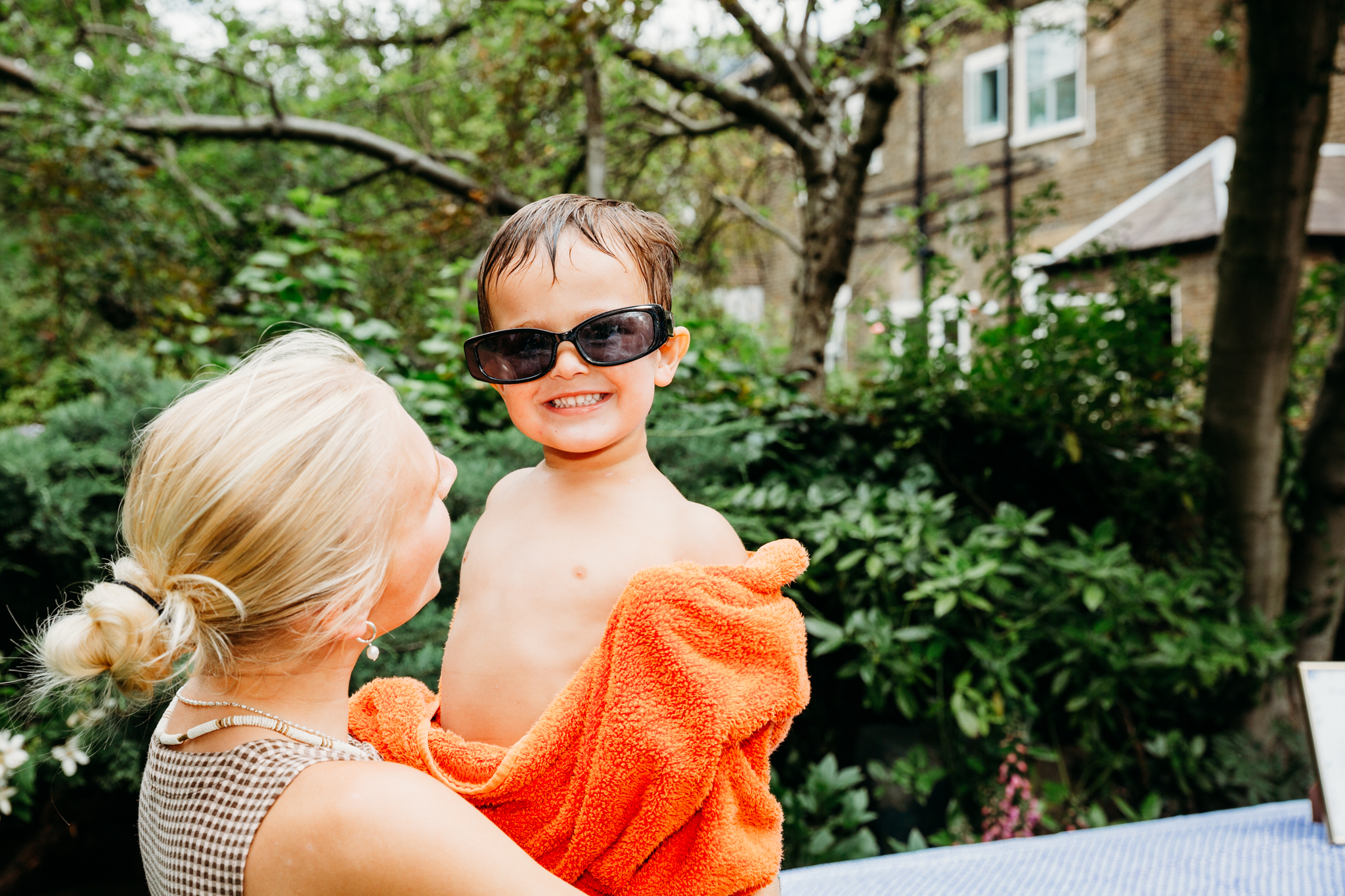 A little boy in an orange towel and dark glasses.