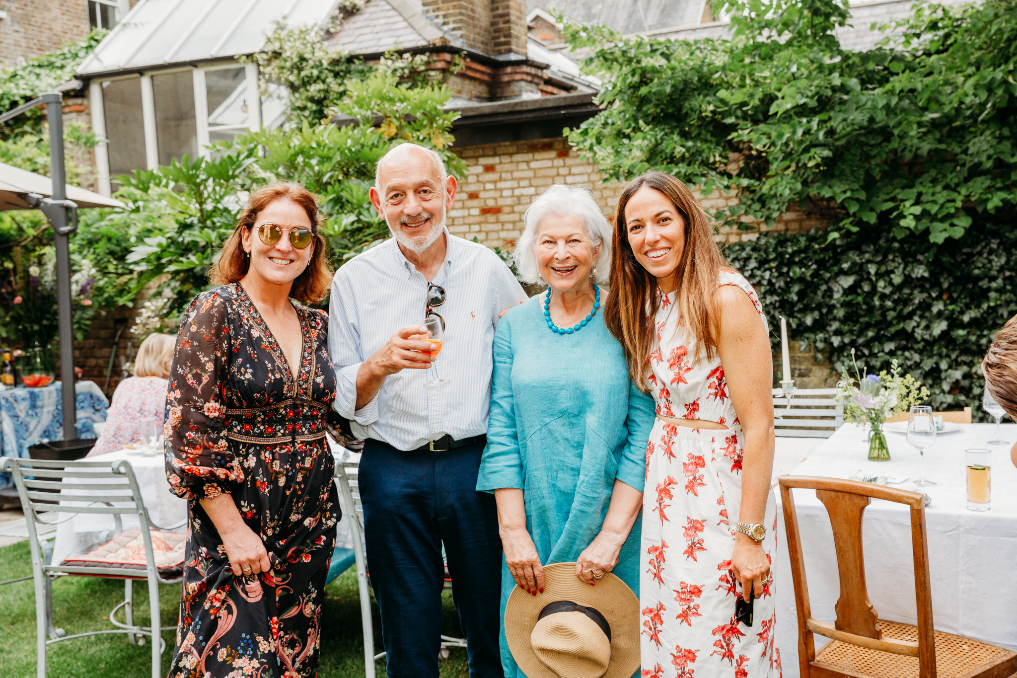 4 people posing for a photo during a birthday party at a backyard.
