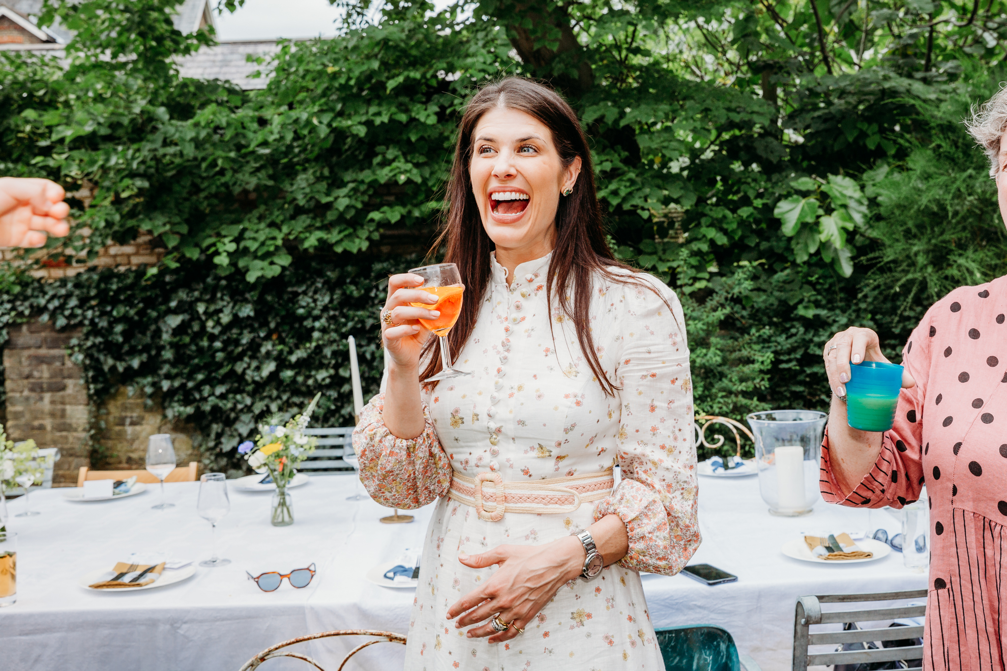 A woman laughing while holding a drink.