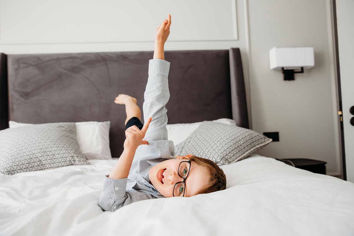 Little boy making silly facew while lying in bed.