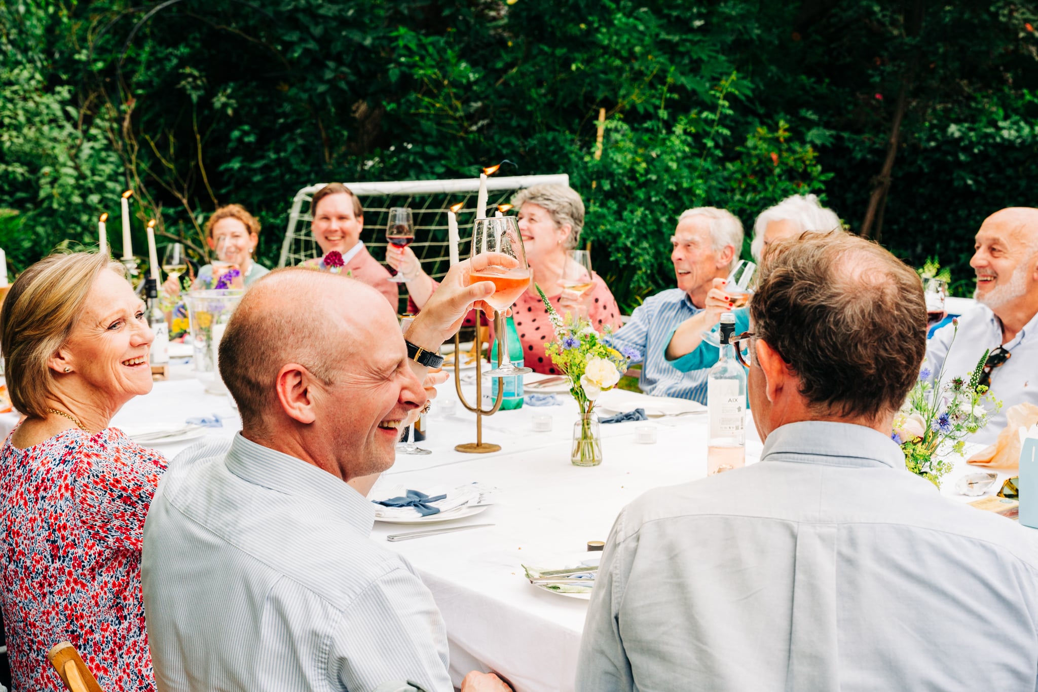 Birthday photography. Wine glasses rising for a toast during celebration dinner at a back yard.