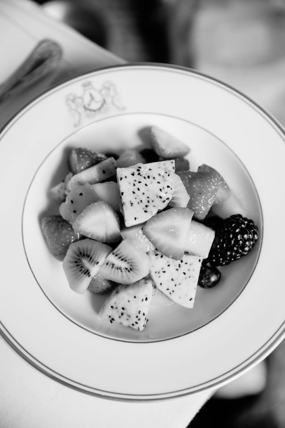 A black and white photo of some fruit salad in a porcelain bowl.