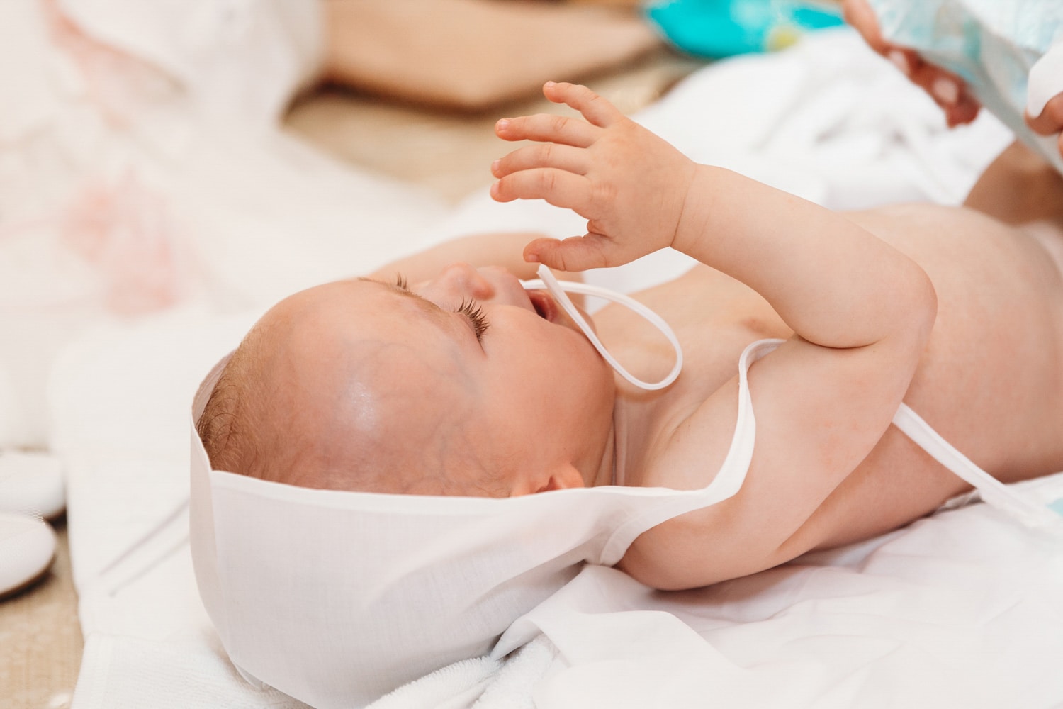 Baptism photographer London. Little girl being dresses after her christening.