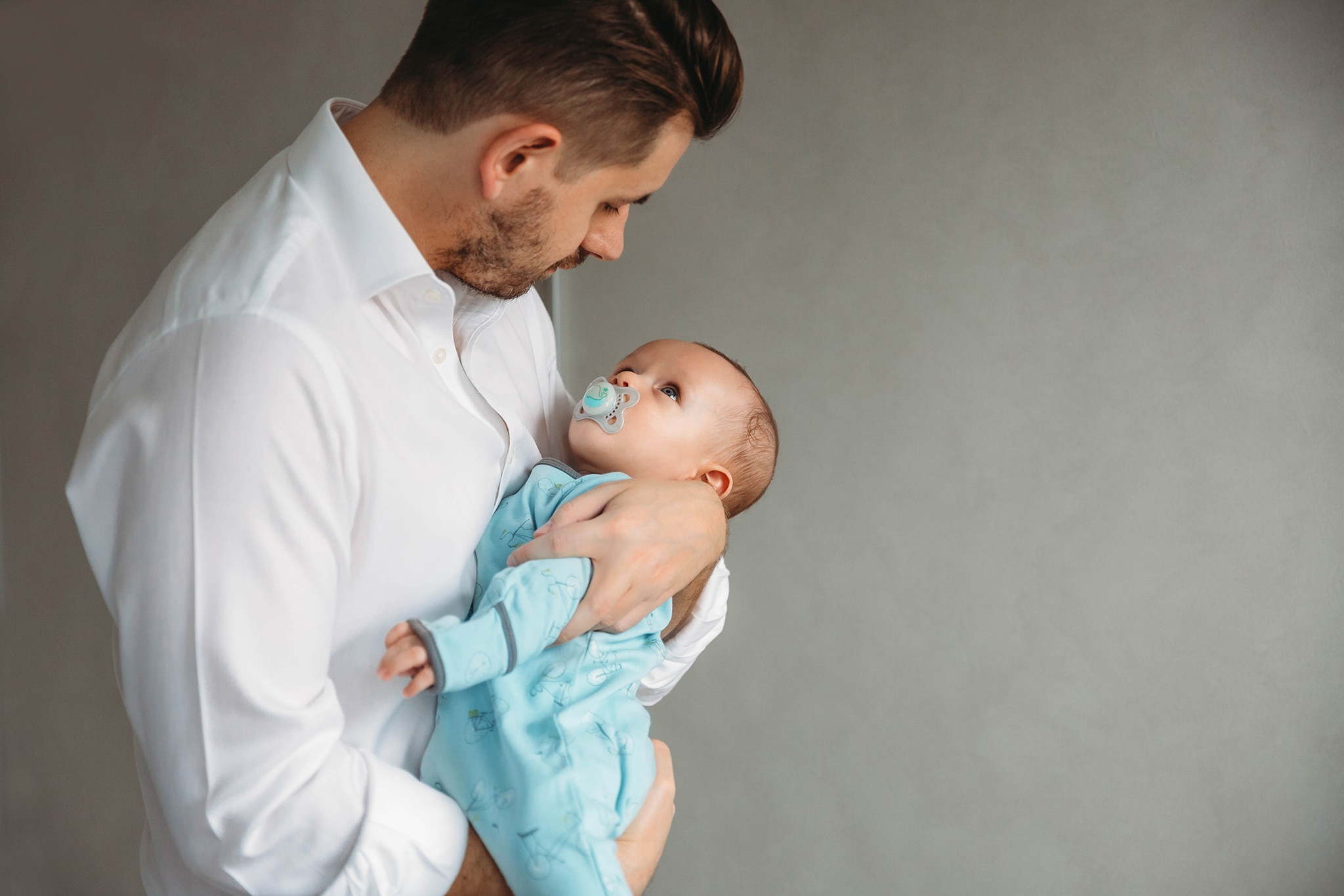 Family photography. Dad holding his baby while baby is staring at him.