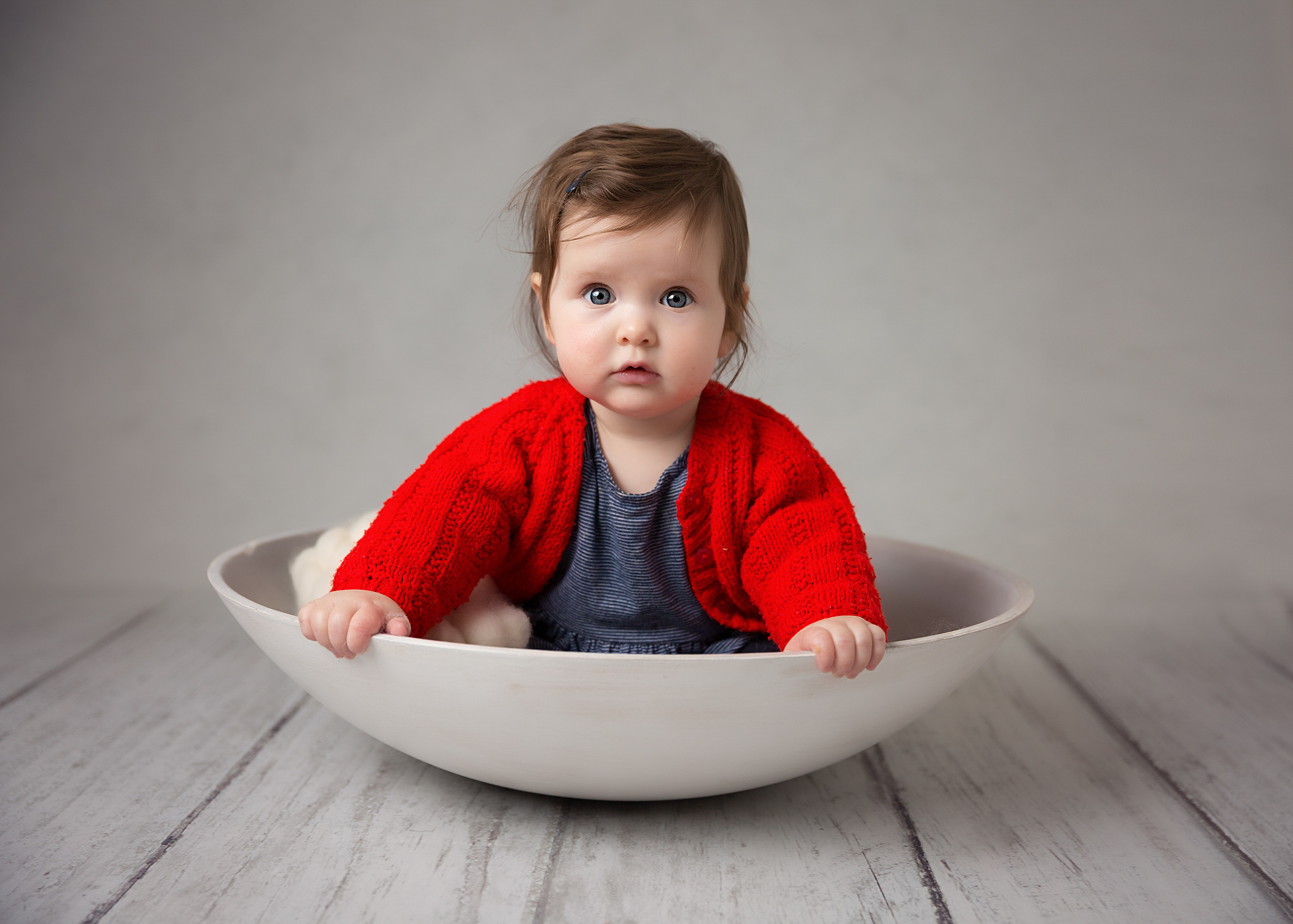 Little toddler girl posing for photo in bowl looking at the camera.