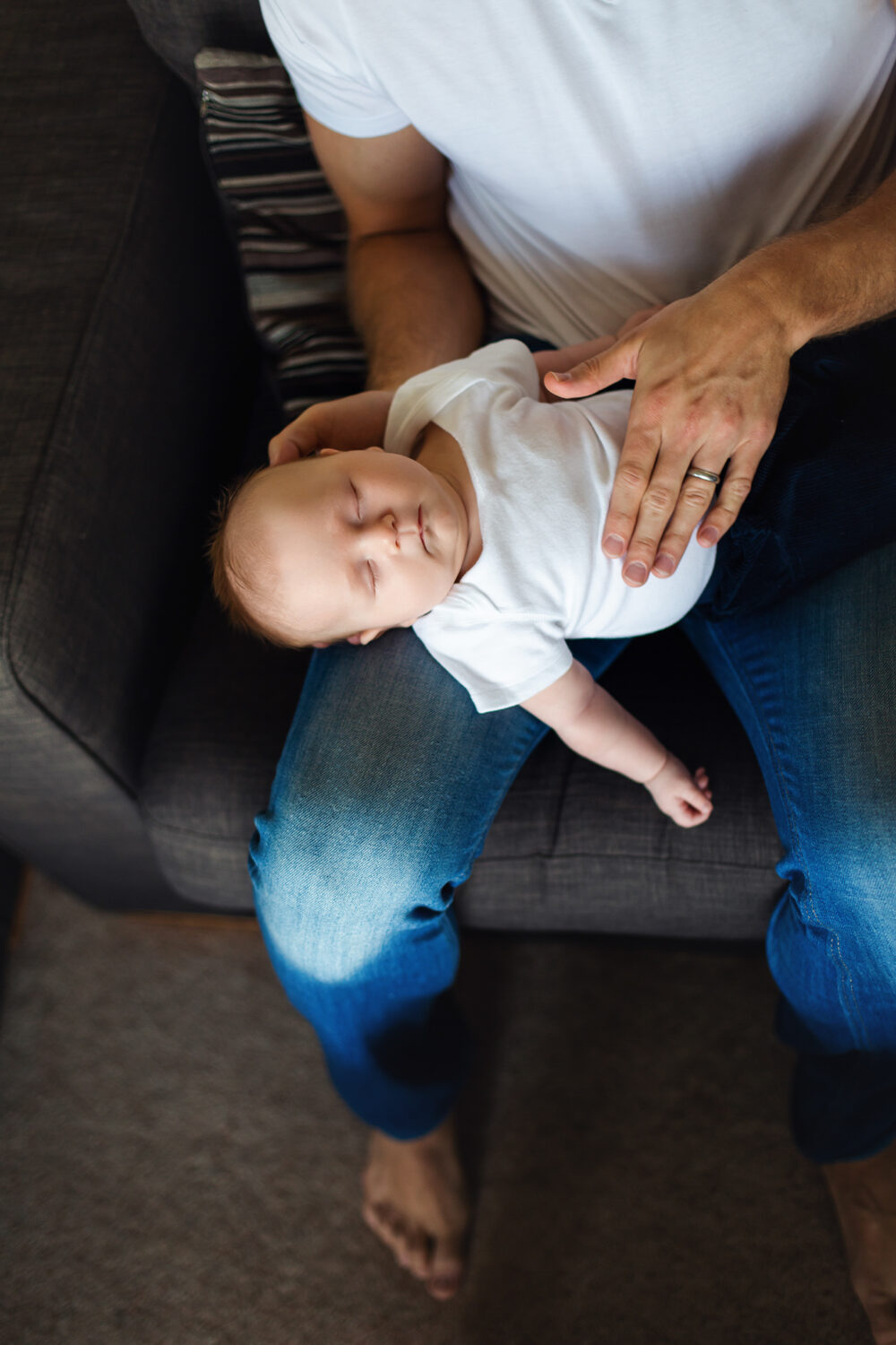Baby sleeping on dad's lap, top view, beautiful light.