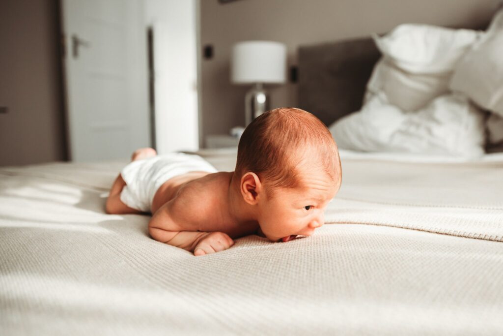 Newborn baby on his tummy trying to support himself.