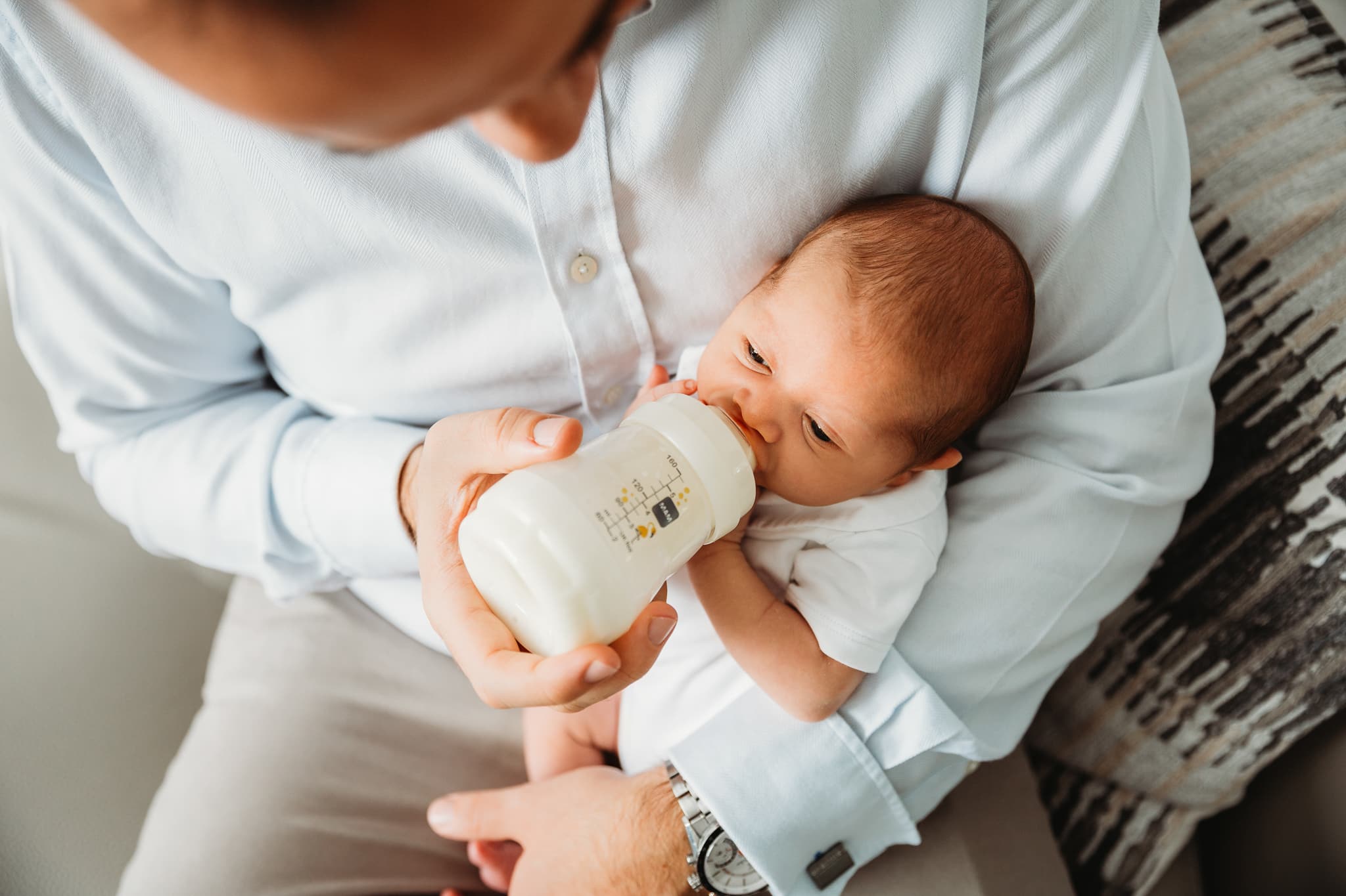 Dad feeding his newborn baby.